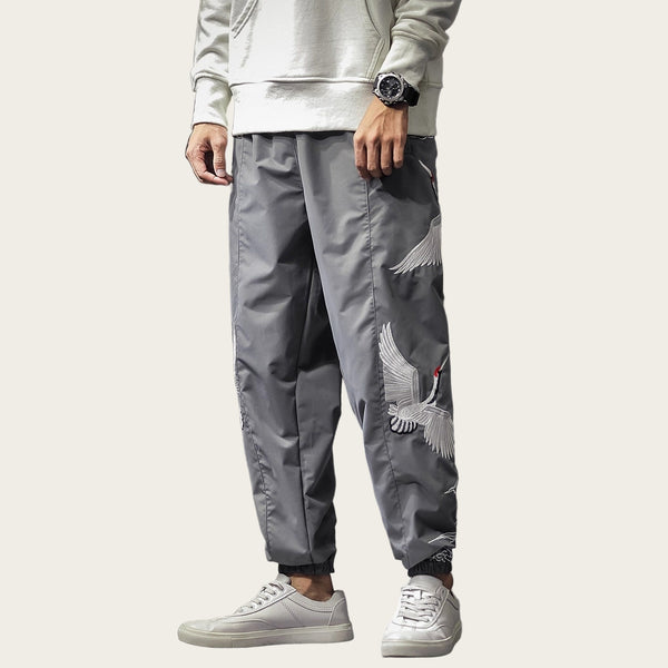 Person wearing gray pants with embroidery in a room setting