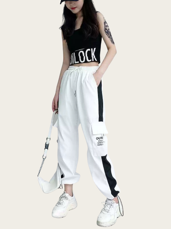 Person wearing a black sleeveless top with 'UNLOCK' text and white pants with black accents on a light gray background.