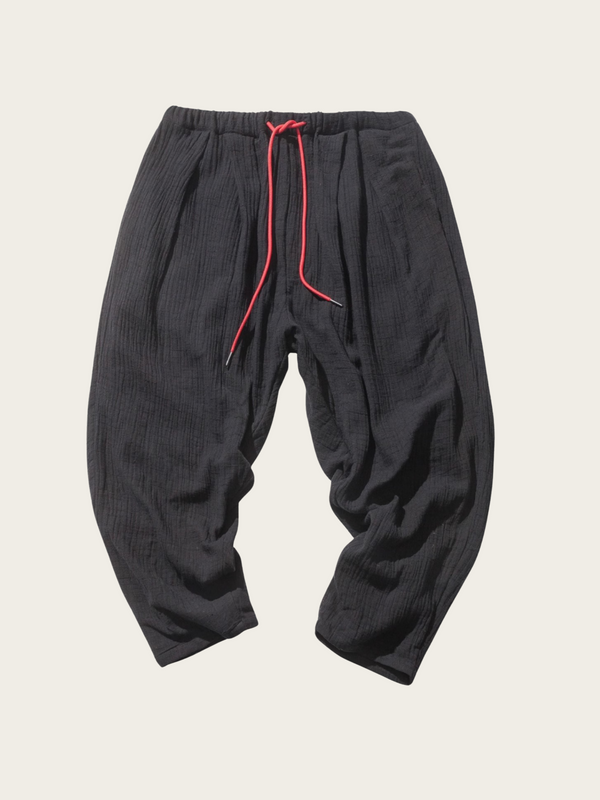 Black baggy pants with red drawstring on a light beige background