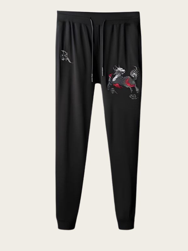Black jogger pants with embroidered designs on a light gray background