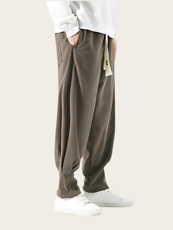 Person wearing brown pants and white shoes on a plain background