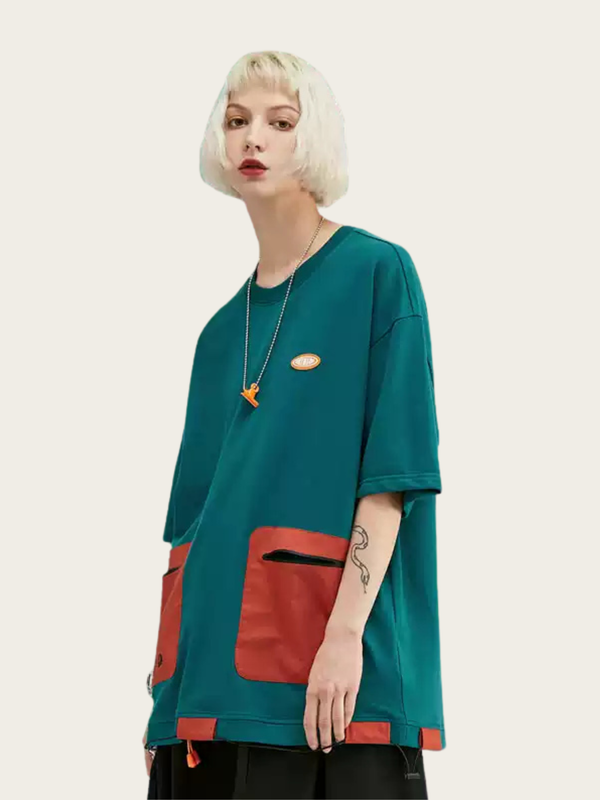 Person wearing a teal oversized shirt with red pocket on a beige background