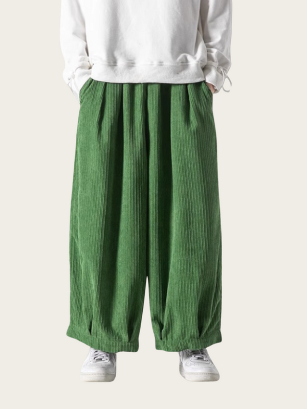 Green wide-leg pants worn with a white sweatshirt on a light gray background