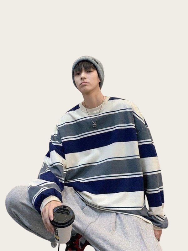Person wearing a striped sweater and holding a coffee cup against a plain background