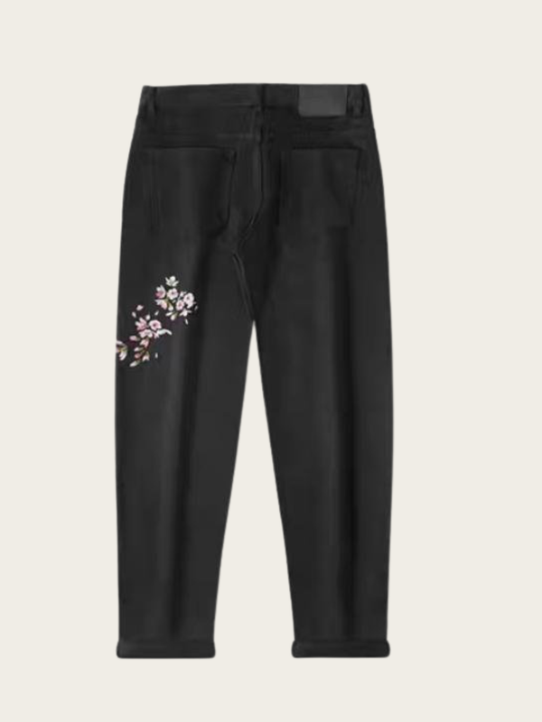 Black jeans with floral embroidery on a beige background