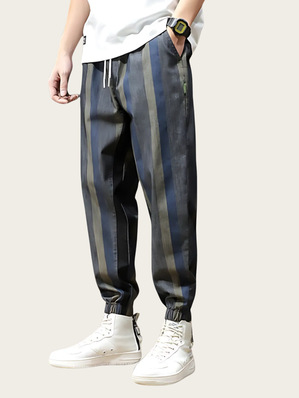 Person wearing striped pants and white sneakers on a plain background