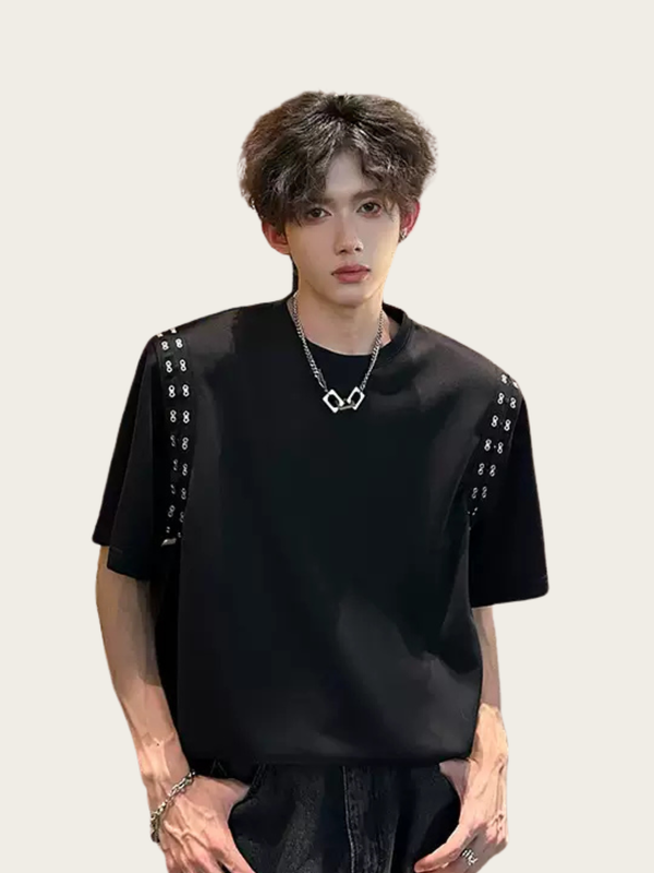 Person wearing a black outfit with decorative elements on a plain background