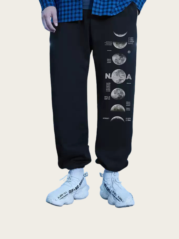Person wearing black sweatpants with NASA moon phase design on a beige background