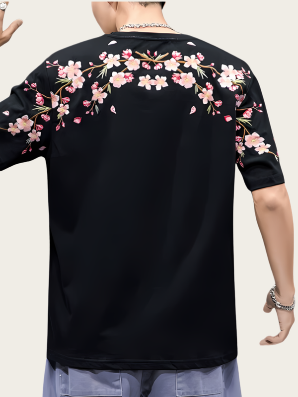 Black shirt with pink floral patterns on sleeves and back, worn by a person.