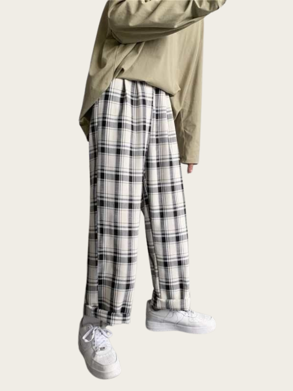 Person wearing plaid pants and a beige jacket on a white background