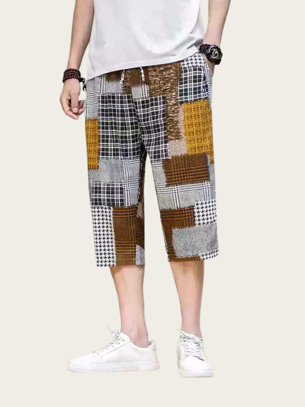 Person wearing a patchwork patterned shorts on a plain background