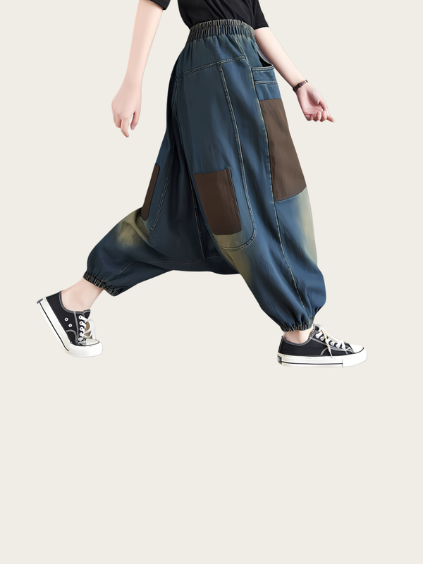 Person wearing patchwork harem pants on a plain background