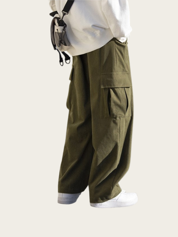 Person wearing olive green cargo pants on a plain background