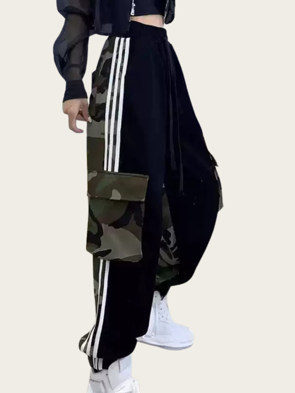 Person wearing black and camouflage pants with white stripes on a beige background