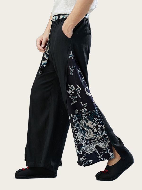 Person wearing black wide-leg pants with dragon embroidery on a plain background