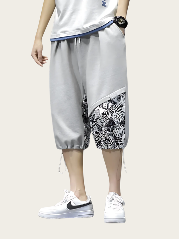 Person wearing gray shorts with a black and white pattern and white sneakers on a light gray background