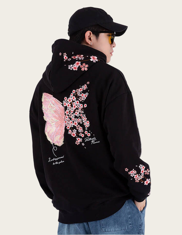 Person wearing a black hoodie with pink floral designs on a white background
