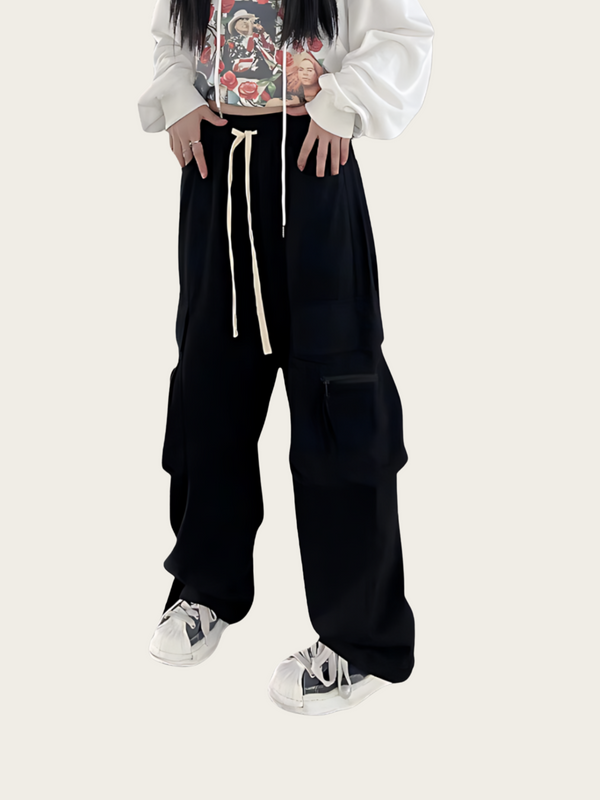 Person wearing black cargo pants with a white shirt and colorful graphic design on a light gray background