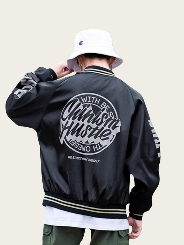 Person wearing a black jacket with text on the back, standing against a plain background