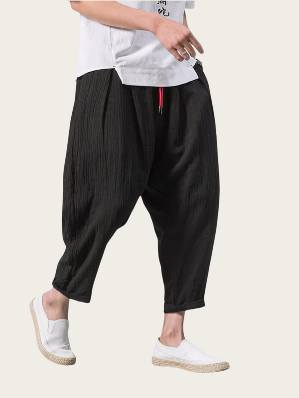 Person wearing black wide-leg pants with a white shirt on a light background