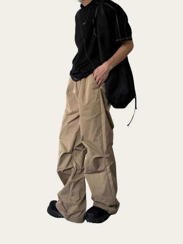 Person wearing beige cargo pants and a black shirt on a white background