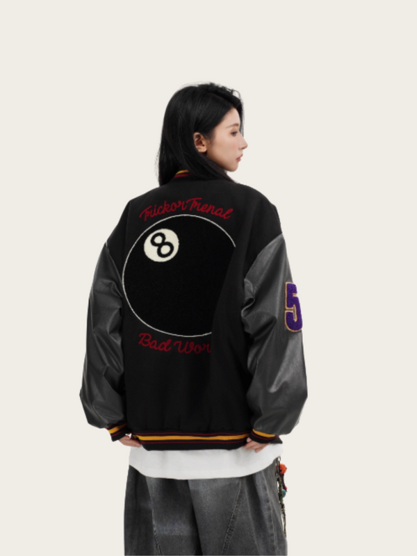 Person wearing a black and gray jacket with text and numbers on the back, standing against a light background.