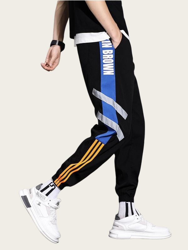 Black jogger pants with colorful stripes worn by a person on a beige background