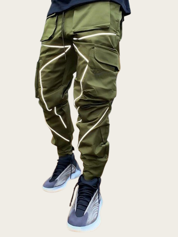 Green cargo pants with reflective stripes worn by a person on a beige background