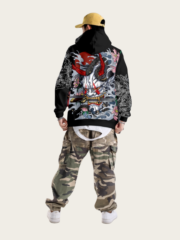 Person wearing a black hoodie with colorful designs and camouflage pants on a white background
