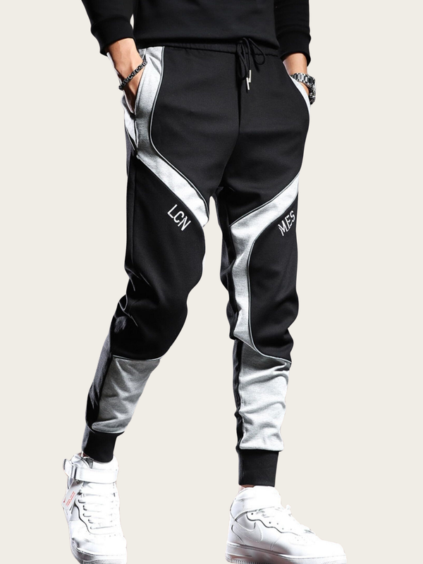 Black and white jogger pants with 'LCN' branding worn by a person on a light gray background
