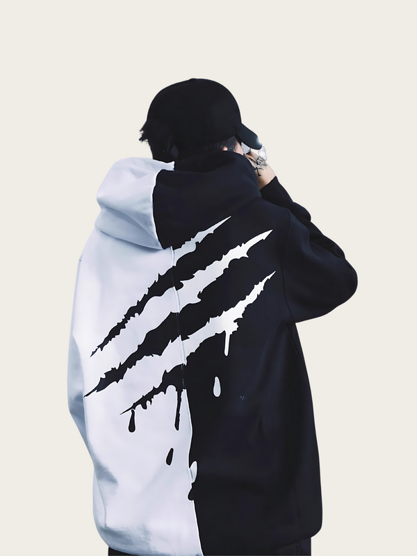 Person wearing a black and white hoodie with a claw mark design on the back against a beige background