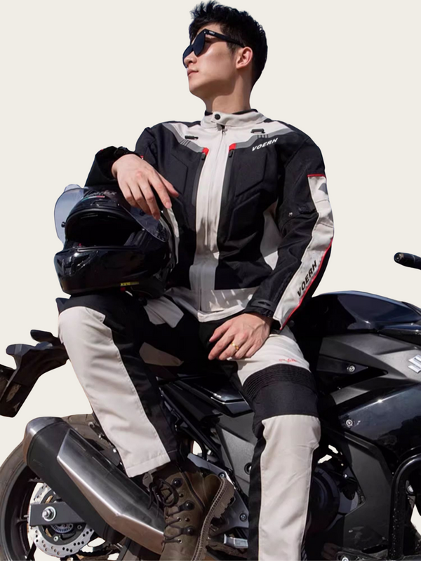 Person wearing a motorcycle jacket sitting on a motorcycle with a helmet.