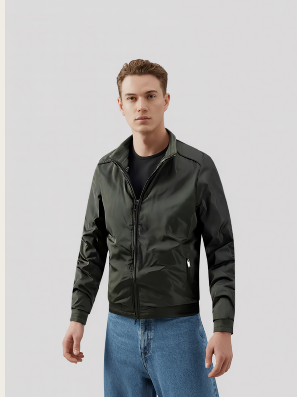 Man wearing a dark green jacket and blue jeans on a light gray background