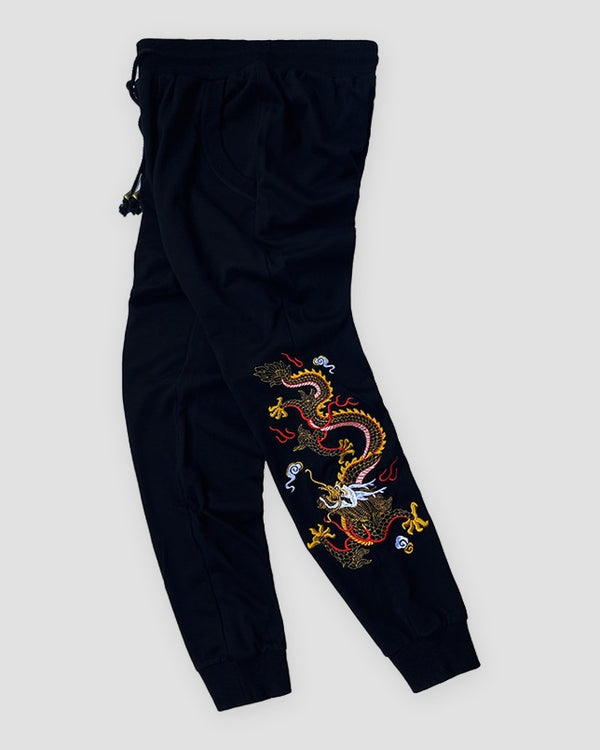 Black jogger pants with a dragon embroidered down one lower leg, front view