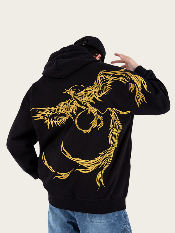 Person wearing a black hoodie with gold dragon design on the back against a white background