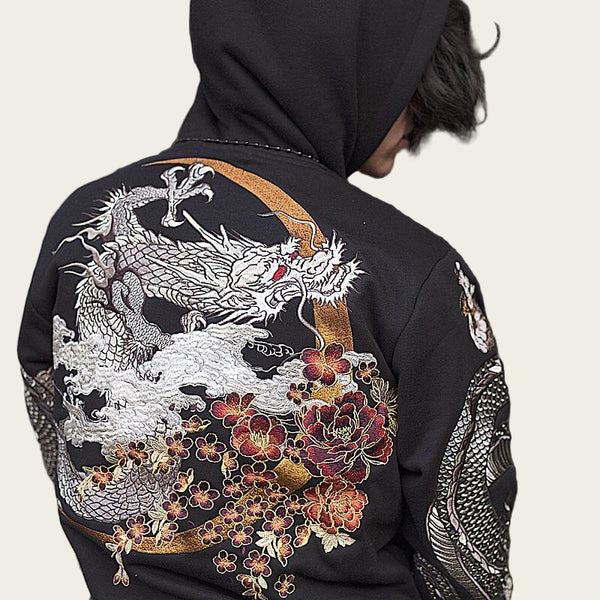 Person wearing a black jacket with dragon and floral embroidery.