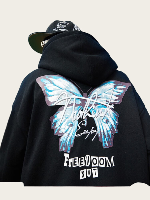 Person wearing a black hoodie with a colorful design on the back against a blue sky.