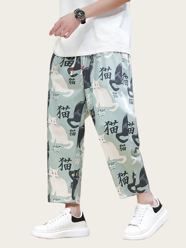 Person wearing light green pants with cat print and white sneakers on a neutral background