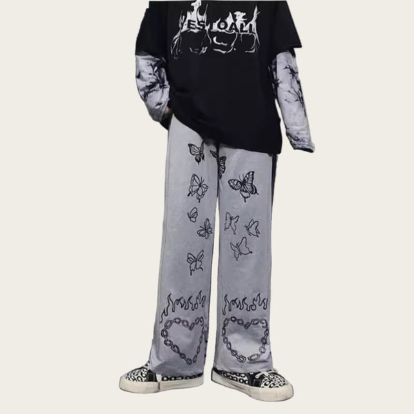 Person wearing a black oversized t-shirt and light gray pants with designs