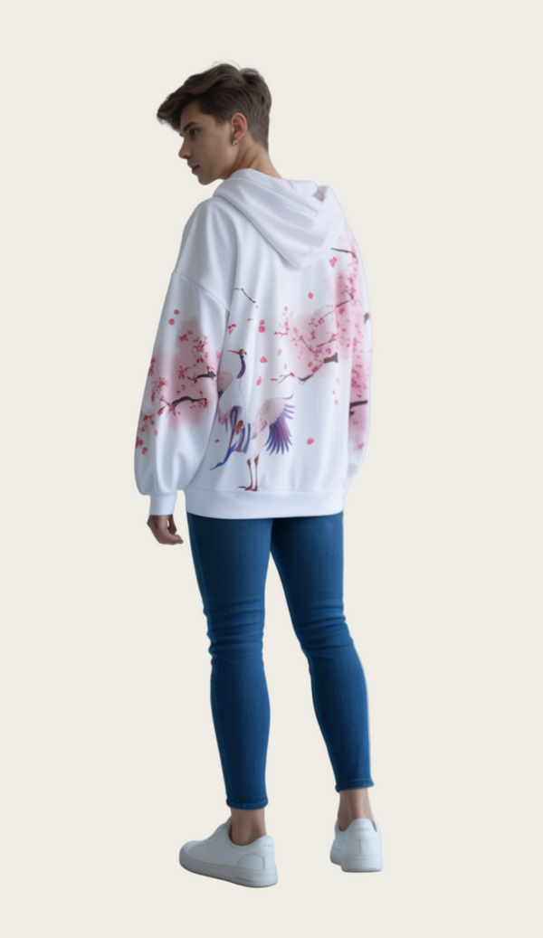 Person wearing a white hoodie with pink floral and bird design on a plain background