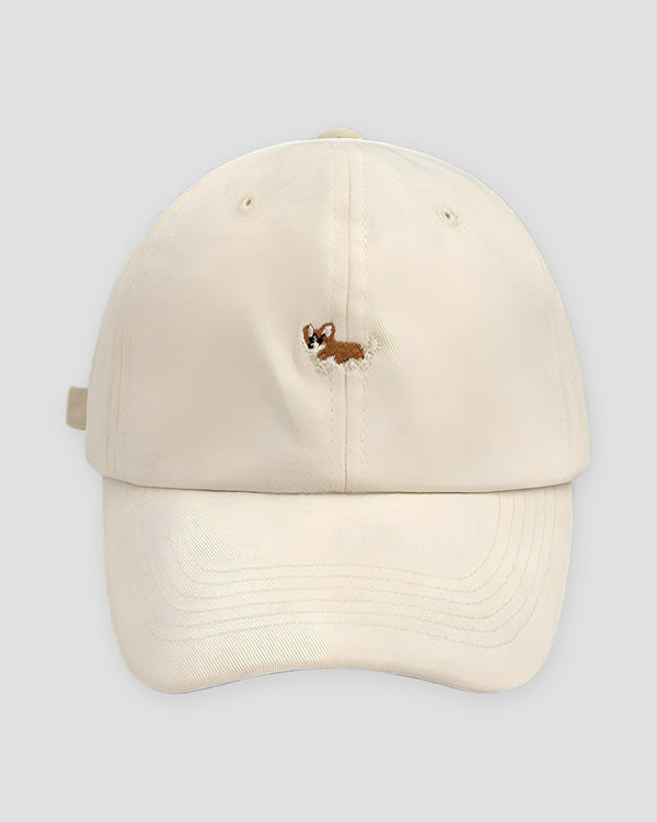 Cream cotton baseball cap with a small embroidered corgi on the front and a curved brim