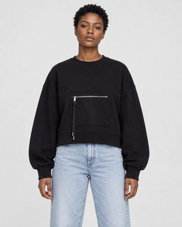 Model wearing the black cropped sweatshirt with light-wash jeans, front view