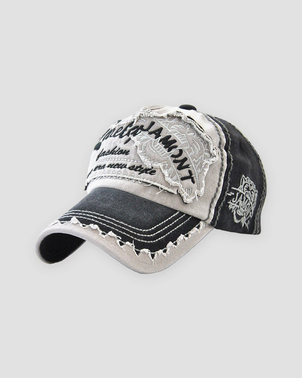 Black distressed patch baseball cap, three-quarter view, frayed stone patch with script lettering