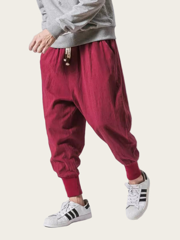 Person wearing red baggy pants and white sneakers on a light gray background