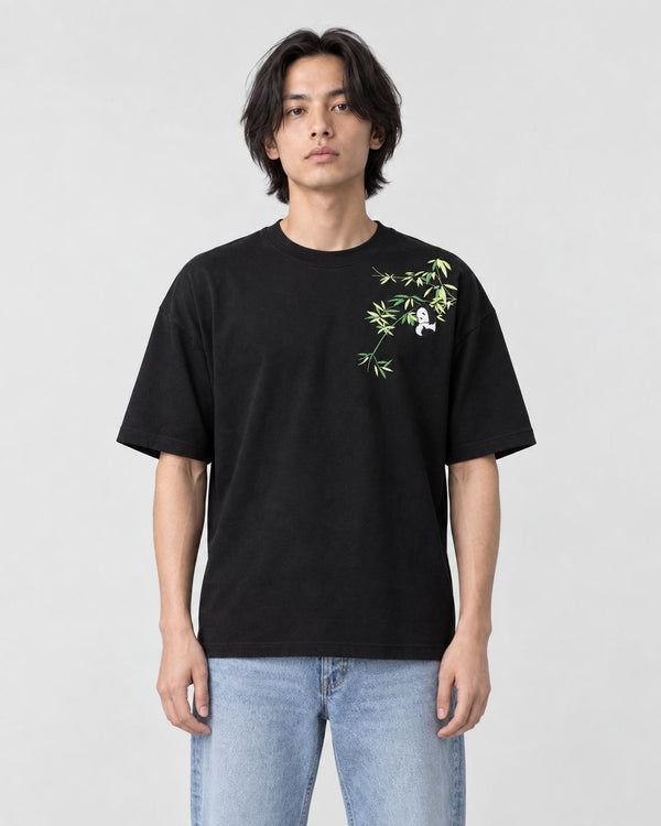 Model wearing the black bamboo and panda embroidered T-shirt with light jeans and white sneakers, front view