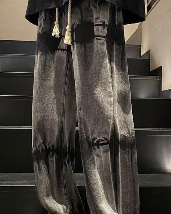Banded charcoal tie-dye jeans with a cream rope drawcord and ankle cords, worn standing on stairs