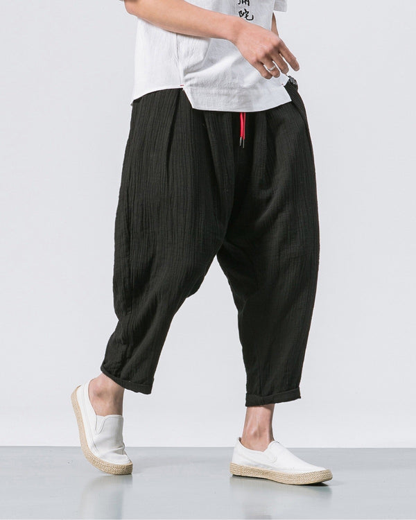 Black crinkled harem pants with a red drawcord and rolled cuffs, worn with a white tee and white slip-on shoes