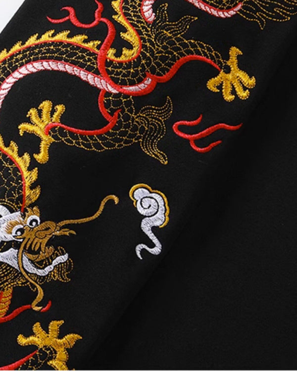 Close view of the dragon embroidered down the sleeve in gold, pink, red and white thread with white clouds on black cotton