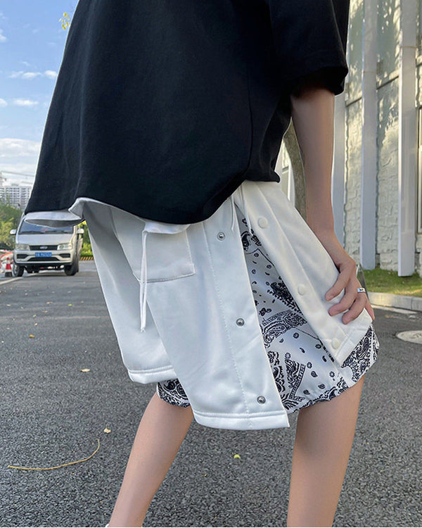 White snap-side shorts with the outer layer lifted to show the black-and-white paisley layer underneath