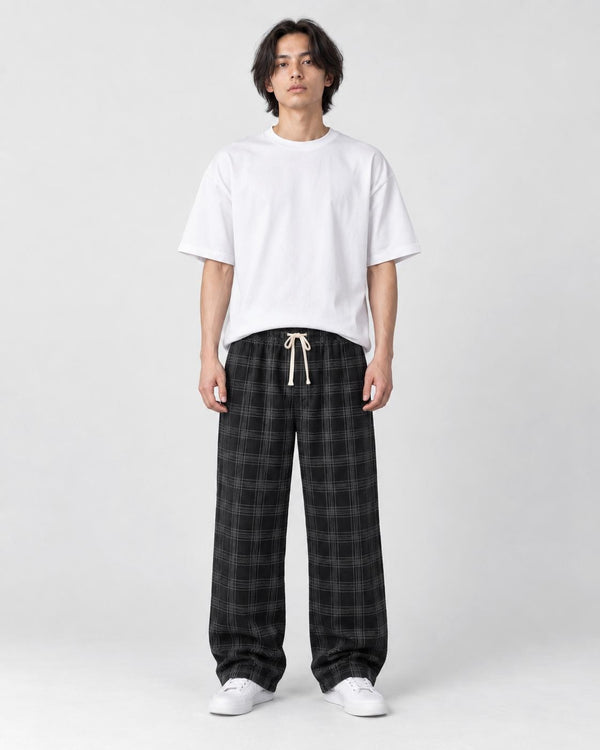 Man in black plaid wide-leg drawstring pants, white tee and white sneakers, full length
